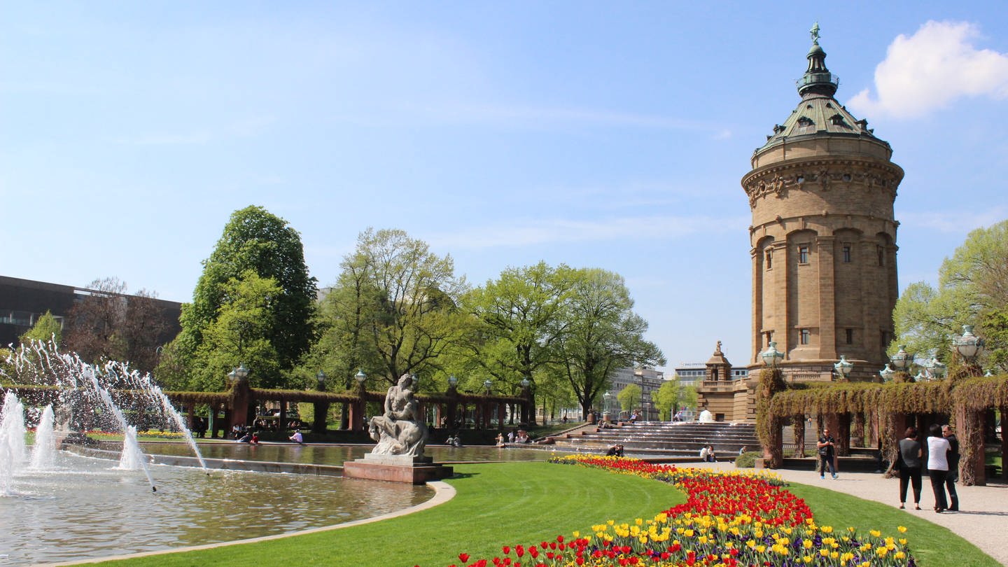 Passanten spazieren am Wasserturm in Mannheim