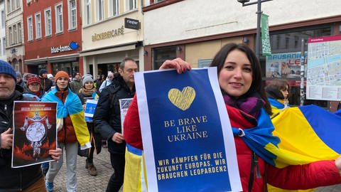 Eine Frau hält ein Plakat in die Höhe. Darauf steht: "Wir kämpfen für die Zukunft der Ukraine. Wir brauchen Leoparden 2".  