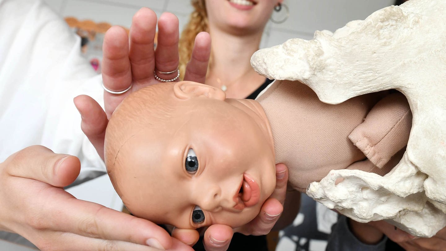 In einer Hebammenschule lernen zukünftige Hebammen die Geburtsmechanik mithilfe einer Puppe.