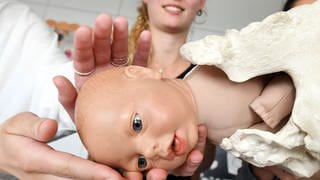 In einer Hebammenschule lernen zukünftige Hebammen die Geburtsmechanik mithilfe einer Puppe. 