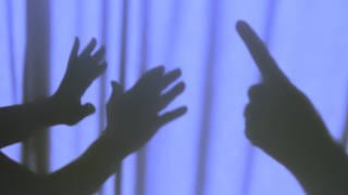 Zwei Hände im Schatten versuchen sich gegen drohende Hand zu wehren