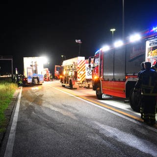 Mehrere Feuerwehrfahrzeuge stehen nebendem Lkw.