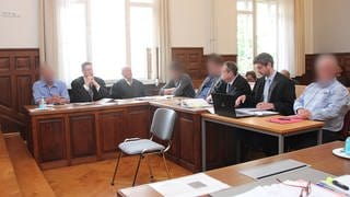 Vier Angeklagte sitzen mit ihren Anwälten im Amtsgericht Weinheim.