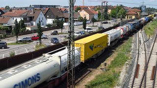 Auf der Bahnstrecke Karlsruhe-Mannheim fährt ein Güterzug an Häusern vorbei. 
