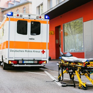 Eine leere Trage steht vor einem Rettungswagen.