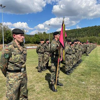 Ein Soldat desPanzerbatallion 363 Hardheim hält eine Fahne, neben ihm Kameraden: Etwa 300 Soldatinnen und Soldaten werden zu ihrem Einsatz nach Litauen verabschiedet. 