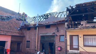 Die Feuerwehr löscht auf einem Leiterwagen den Dachstuhl des Hauses in Elztal-Dallau.