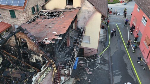 Das Dach des Hauses und ein Anbau sind ausgebrannt, am Nachbarhaus sind Rußspuren zu sehen. 