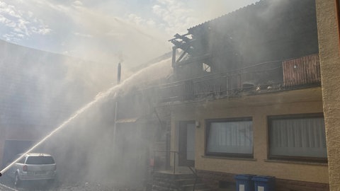 Die Feuerwehr löscht den brennenden Dachstuhl. Es qualmt stark. 