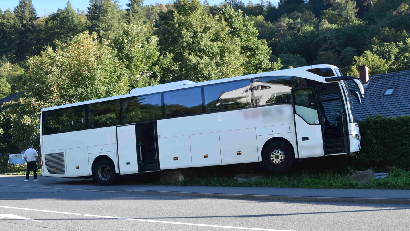 Ein Reisebus hängt auf großen Steinen fest vor einem Hotel