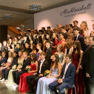 Junge Männer und Frauen lassen sich auf dem Abschlussball in ihren Anzügen und Ballkleidern fotografieren.