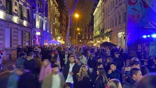 Viele Menschen schlendern nachts durch eine bunt erleuchtete Straße im Stadtteil Jungbusch beim Kulturspektakel Nachtwandel 