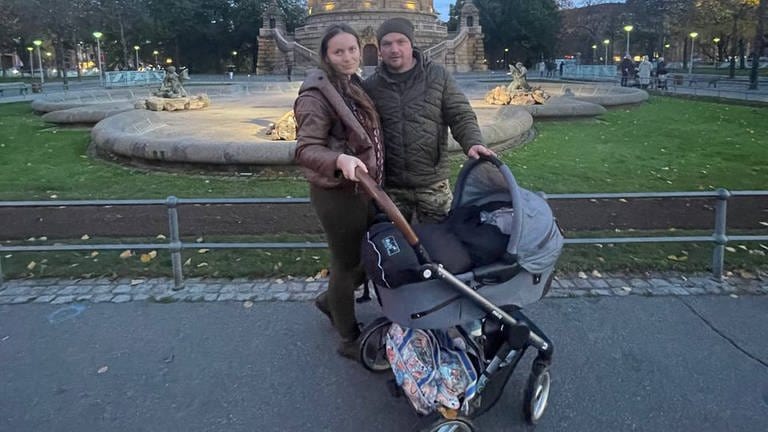 Ukrainischer Vater und Mutter mit Kinderwagen vor Wasserturm in Mannheim