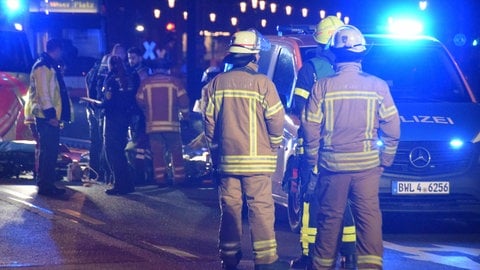 Rettungskräfte der Feuerwehr stehen vor der Straßenbahn der Linie 5A in der Nähe einer Tankstelle. Im Hintergrund stehen Notarzt und Krankenwagen.