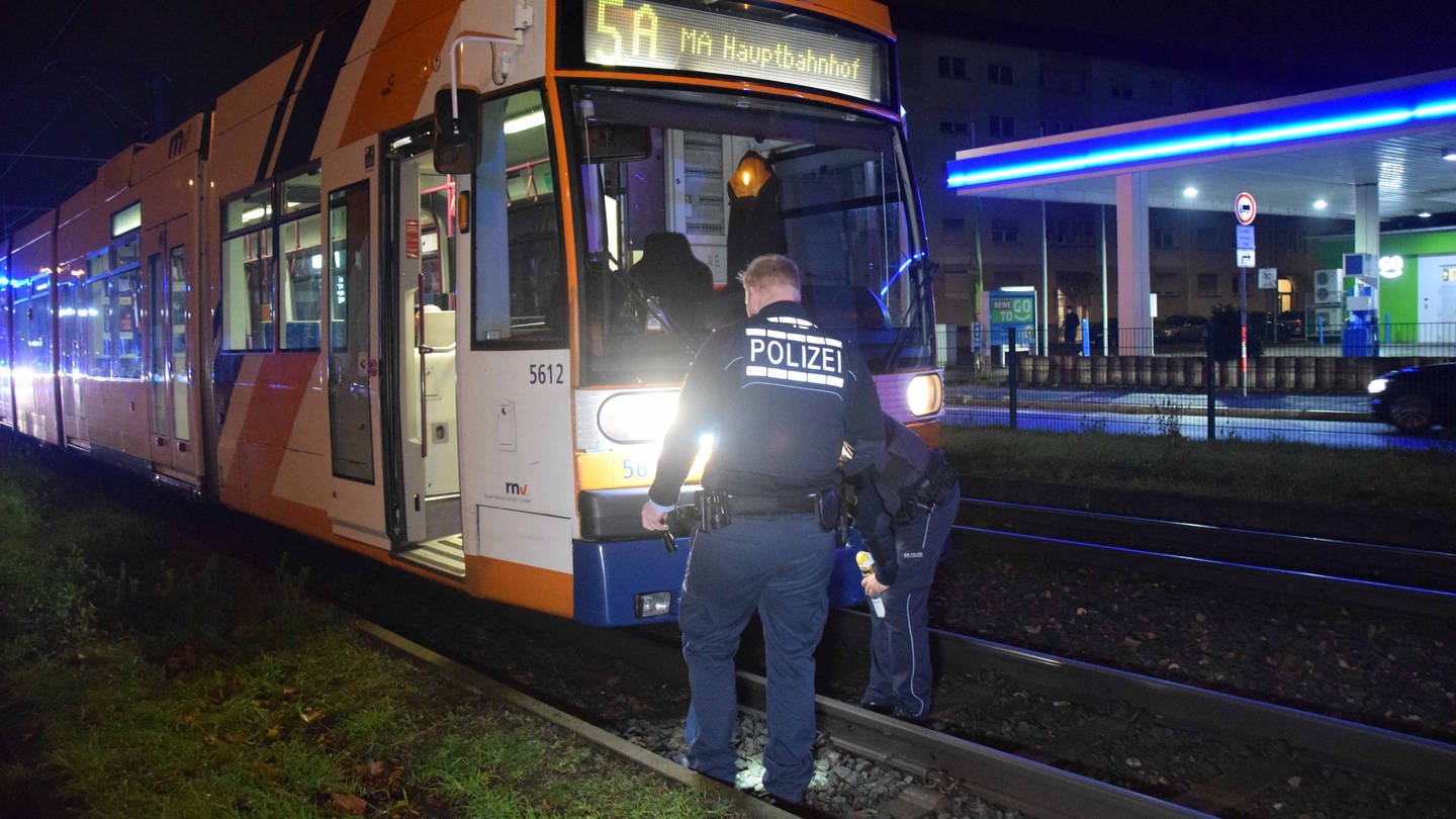 Bei einem Straßenbahnunfall in Mannheim kam ein Mann ums Leben. Zwei Polizisten untersuchen die Straßenbahn.
