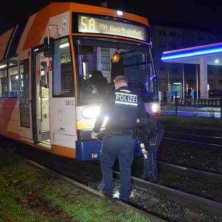 Bei einem Straßenbahnunfall in Mannheim kam ein Mann ums Leben. Zwei Polizisten untersuchen die Straßenbahn.