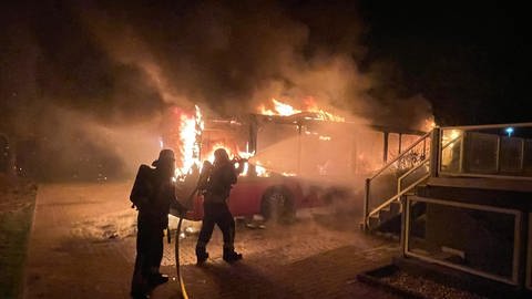 In Rauenberg (Rhein-Neckar-Kreis) löschen die Einsatzkräfte auf einem Hotelgelände einen umgebauten Linienbus, der komplett in Flammen steht.