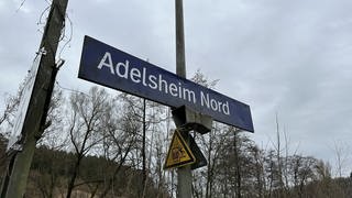 Schild an Bahnübergang und Haltestelle mit Aufschrift Adelsheim-Nord 