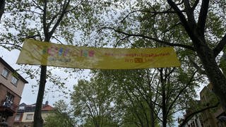 "Vielfalt statt Einfalt"-Banner zwischen Bäumen in Max-Joseph-Straße in Mannheim