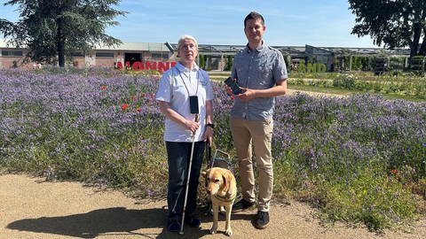 Maria Huber steht zusammen mit ihrem Blindenführhund neben Johannes Britsch, dem Geschäftsführer von contagt