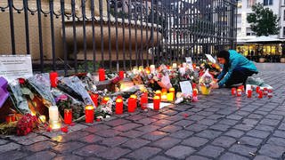 Nach dem Bekanntwerden vom Tod des Polizisten legen am Tatort am Marktplatz Passanten Blumen nieder und zünden Kerzen an. 