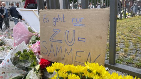 Pappschild mit Aufschrift "Es geht nur zusammen!" am Rand des Marktplatzbrunnens in der Mannheimer Innenstadt