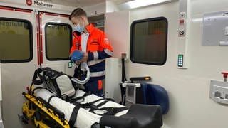 Ein Sanitäter des Malteser Hilfsdienst Heidelberg (MHD) bereitet in einem Krankenwagen einen Krankentransport vor