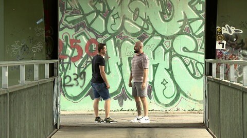 Pfleger Timo Strianese mit Mann vor einer Graffiti-Wand 