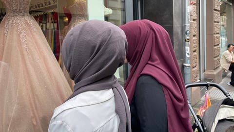 Zwei muslimische Frauen mit Kopftuch stehen vor einem Geschäft in Mannheim.
