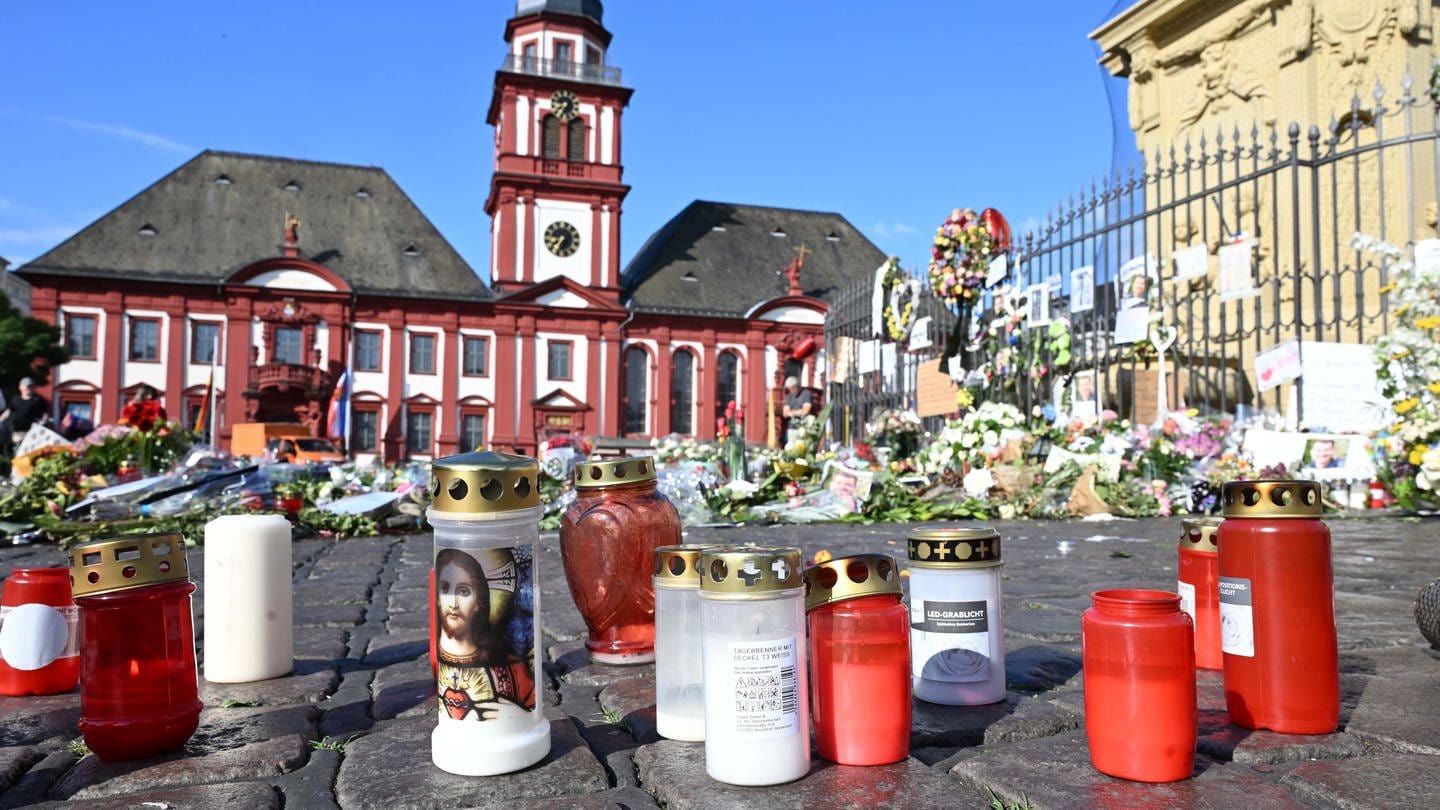 Blumen und Kerzen liegen auf dem Marktplatz in Mannheim zum Gedenken an einen getöteten Polizisten. Ende Mai wurde auf dem Platz ein Polizist bei einem Messerangriff getötet.