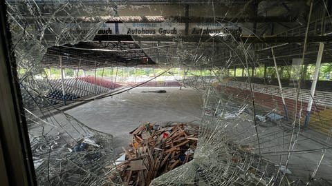 Das alte Eisstadion in Mannheim wird nach und nach abgerissen. Duch eine geborstene Scheibe sieht man Schutt im Stadion liegen