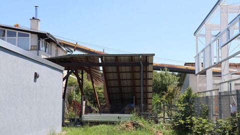 Der Kranausleger liegt auf dem Dach eines Wohnhauses mitsamt Photovoltaikanlage. Ein Gewerbegebäude ist stark beschädigt.