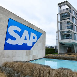 Ein Logo des Softwarekonzerns SAP auf einer grauen Wand vor einem SAP-Gebäude in Walldorf