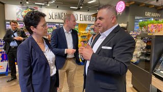 Supermarktbetreiber Sahin Karaaslan führt die baden-württembergische Justizministerin Marion Gentges durch seinen Supermarkt in Mannheim-Käfertal und erklärt, wie Ladendiebe hier vorgehen.