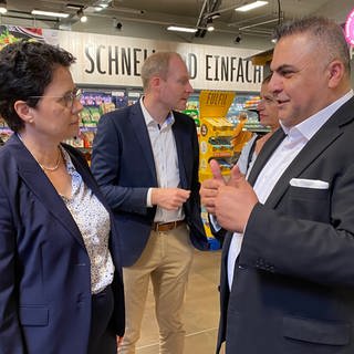 Supermarktbetreiber Sahin Karaaslan führt die baden-württembergische Justizministerin Marion Gentges durch seinen Supermarkt in Mannheim-Käfertal und erklärt, wie Ladendiebe hier vorgehen.