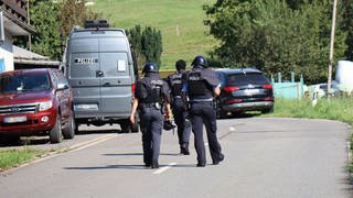 Polizisten in Schutzkleidung auf Straße - In Heiligkreuzsteinach läuft ein größerer Polizeieinsatz