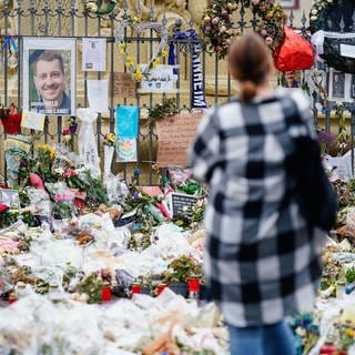 Eine Frau steht am Mannheimer Marktplatz an der Trauerstelle für den getöteten Polizisten Rouven Laur.