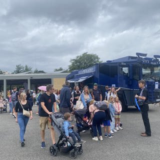 Menschen vor Polizieeinsatzwagen 