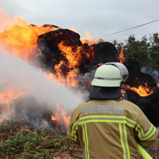 Feuerwehrmann löscht brennende Strohballen