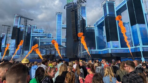 Besucherinnen und Besucher versammeln sich bei dem Glücksgefühle Festival 2024 auf dem Hockenheimring vor der Bühne.