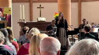 Viele Menschen lauschen der Sängerin in der Kirche.