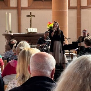 Viele Menschen lauschen der Sängerin in der Kirche.