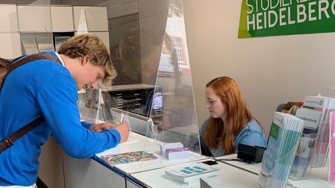 Student Jannis Willert füllt ein Formular beim Studierendenwerk Heidelberg aus