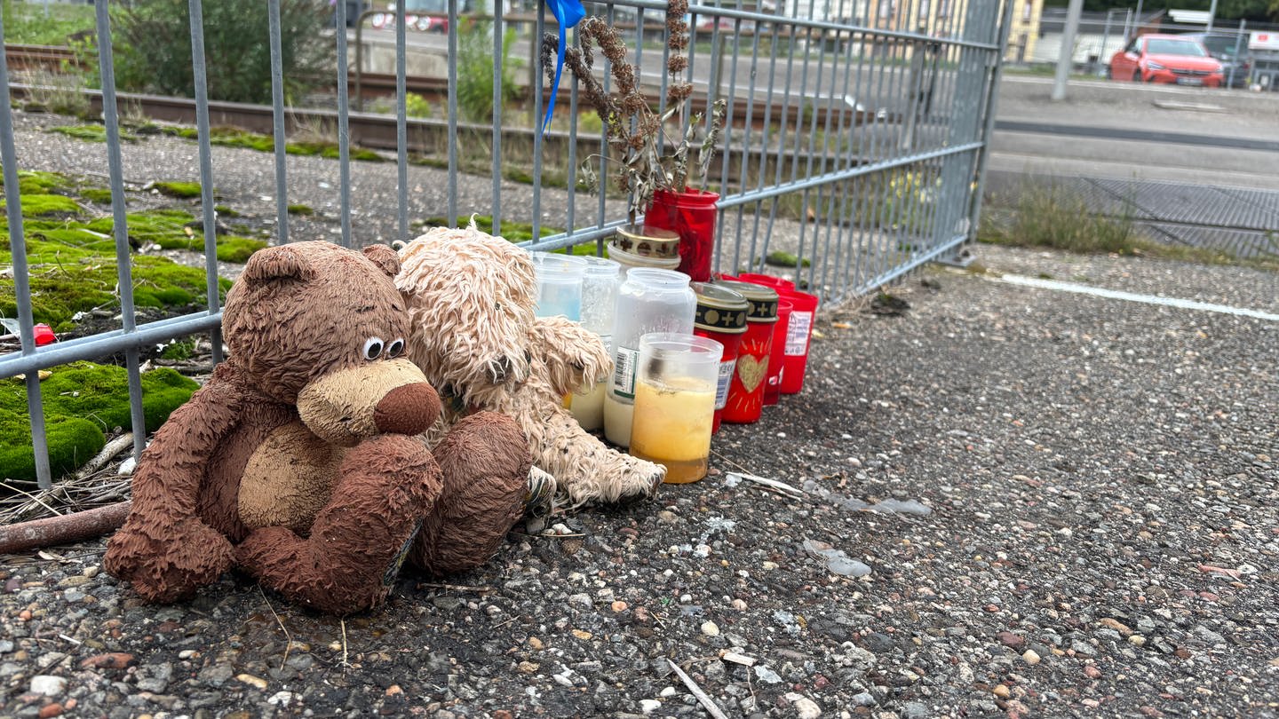 Am Bahngleis liegen Kuscheltiere und Kerzen.