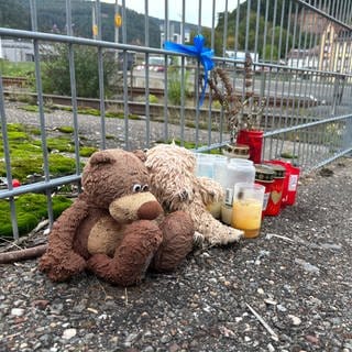 Am Bahngleis liegen Kuscheltiere und Kerzen.