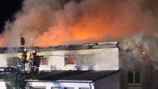 Eine Mehrfamilienhaus steht völlig in Flammen, die Feuerwehr löscht 