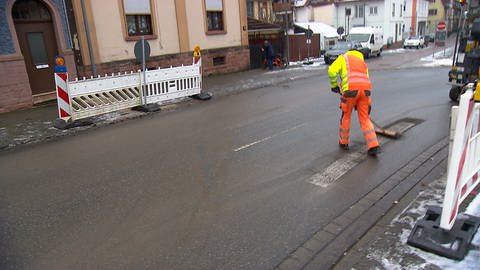 Ein Arbeiter fegt die letzten Reste des Zebrastreifens weg.