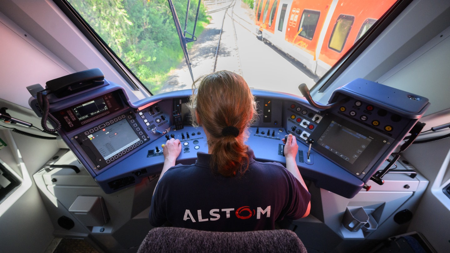 Mitarbeiterin von Alstom an den Schaltknüppeln im Führerstand eines Zugs