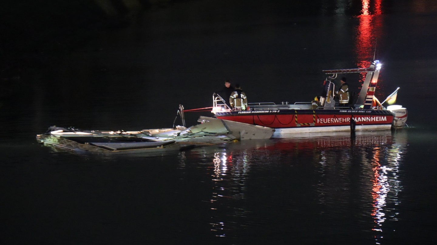 Feuerwehrleute untersuchen von einem Boot aus abgerissene Teile eines Binnenschiffes, die nach dessen Kollision mit einer Brücke in Mannheim auf dem Rhein schwimmen.