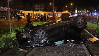 Ein Auto hat sich überschlagen und ist auf dem Dach im Gleisbett der Straßenbahn gelandet